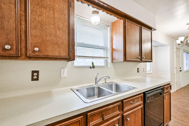 kitchen featuring sink, light hardwood / wood-style flooring, black dishwasher, a notable chandelier, and pendant lighting