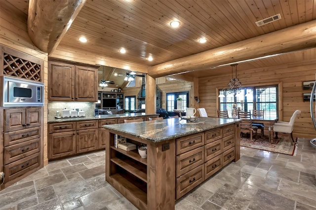 kitchen with stainless steel microwave, a kitchen island, and wooden ceiling