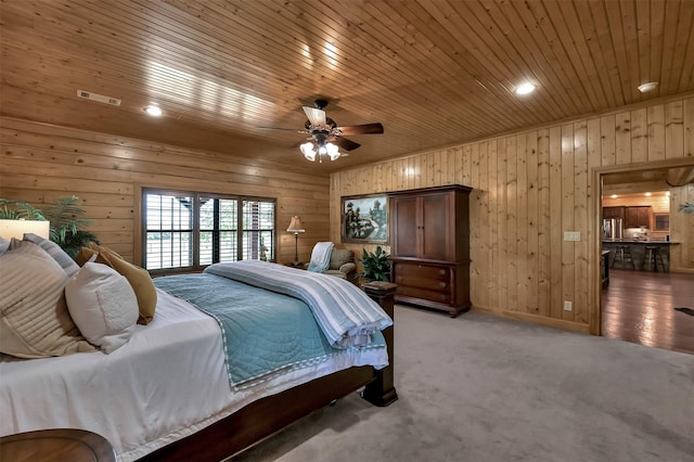 carpeted bedroom with wood ceiling, ceiling fan, and wood walls