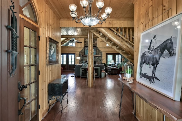 entryway featuring dark wood-type flooring, ceiling fan with notable chandelier, vaulted ceiling, wooden ceiling, and wood walls