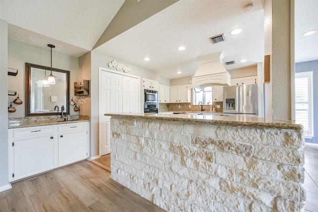 kitchen featuring pendant lighting, white cabinetry, stainless steel appliances, light stone countertops, and light wood-type flooring