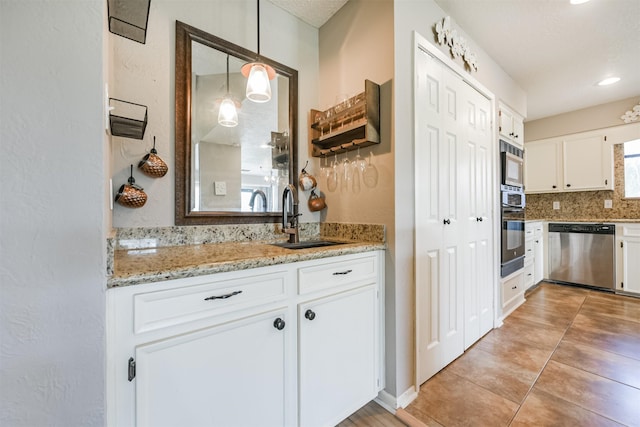 kitchen with white cabinetry, sink, decorative light fixtures, and stainless steel appliances