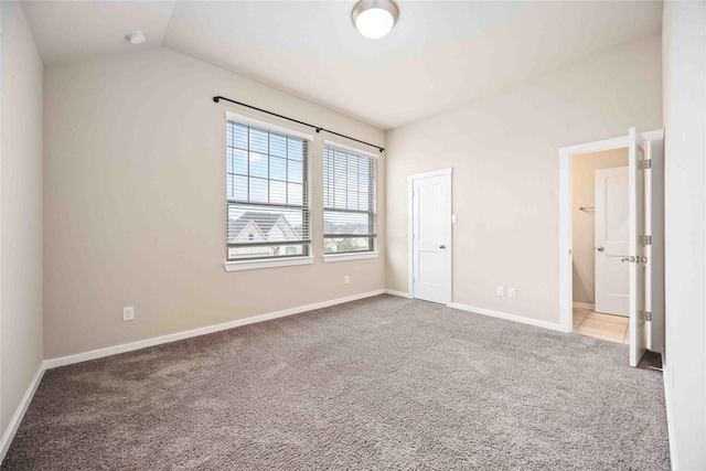 unfurnished bedroom with vaulted ceiling and carpet flooring