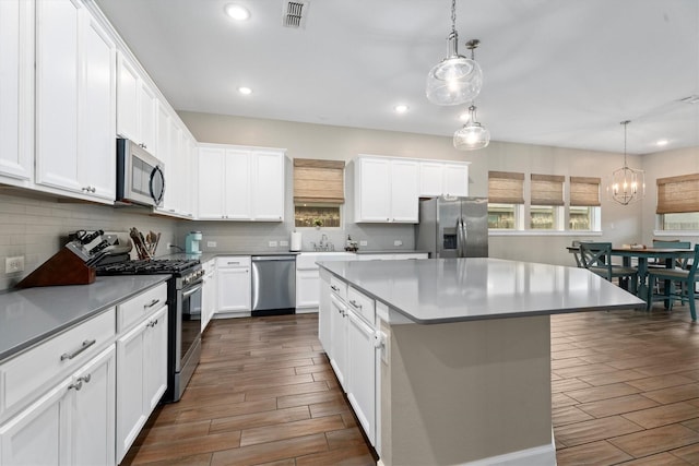 kitchen featuring white cabinetry, hanging light fixtures, stainless steel appliances, and a center island