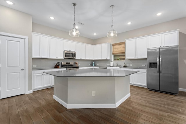 kitchen with white cabinetry, decorative light fixtures, stainless steel appliances, and a center island