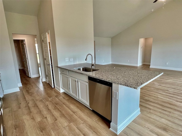 kitchen featuring sink, white cabinetry, light wood-type flooring, stainless steel dishwasher, and light stone countertops