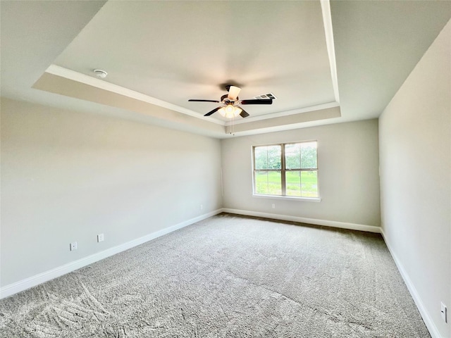 carpeted empty room featuring a raised ceiling and ceiling fan