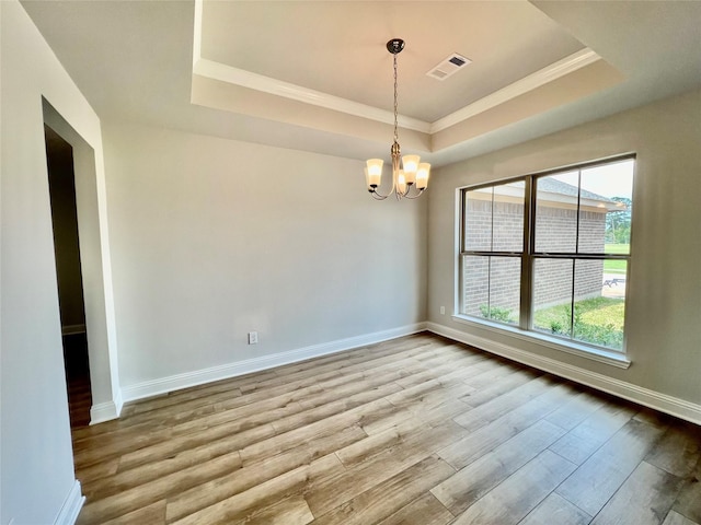 unfurnished room featuring a notable chandelier, a tray ceiling, ornamental molding, and light hardwood / wood-style floors