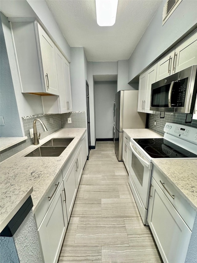 kitchen with light stone countertops, appliances with stainless steel finishes, sink, and white cabinets