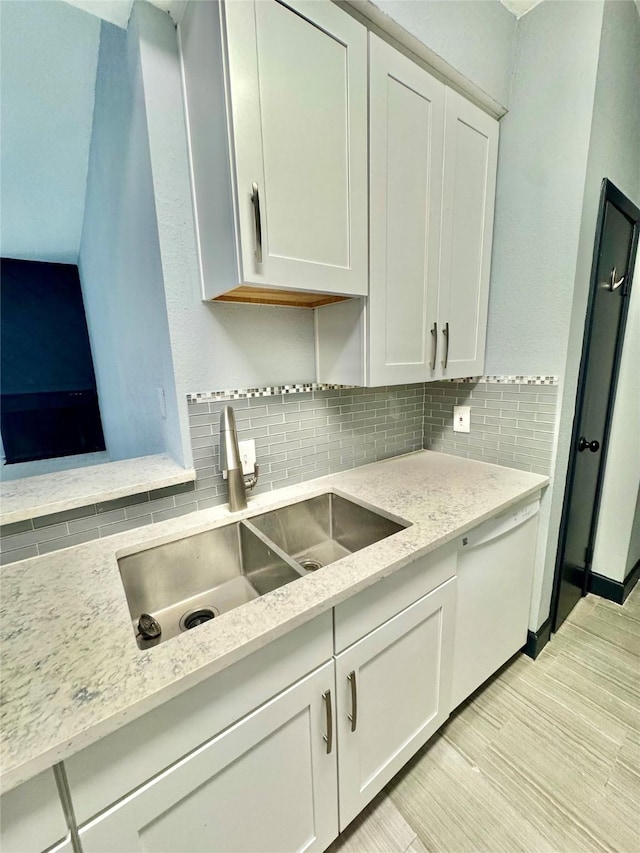 kitchen featuring tasteful backsplash, sink, light stone counters, and white cabinets