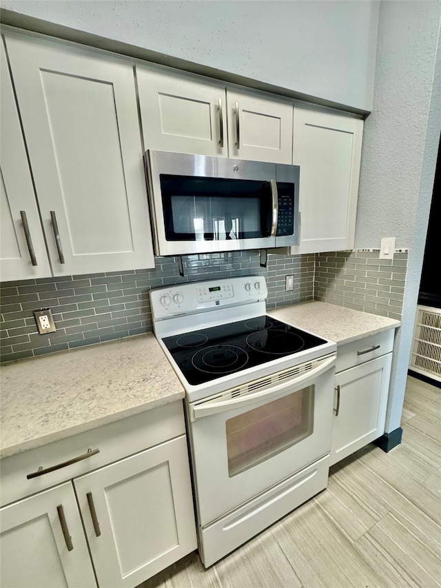 kitchen with white cabinetry, light hardwood / wood-style flooring, white range with electric cooktop, light stone countertops, and decorative backsplash