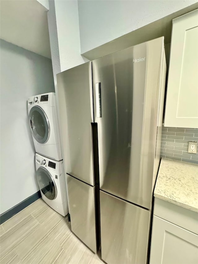 clothes washing area featuring stacked washer / drying machine and light hardwood / wood-style floors