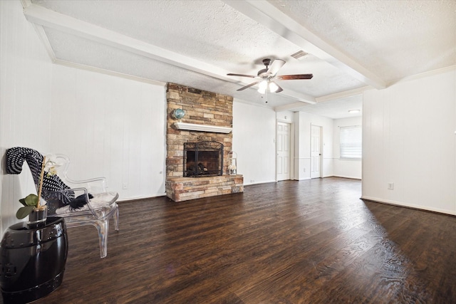 living room featuring a stone fireplace, dark hardwood / wood-style floors, beam ceiling, ceiling fan, and a textured ceiling