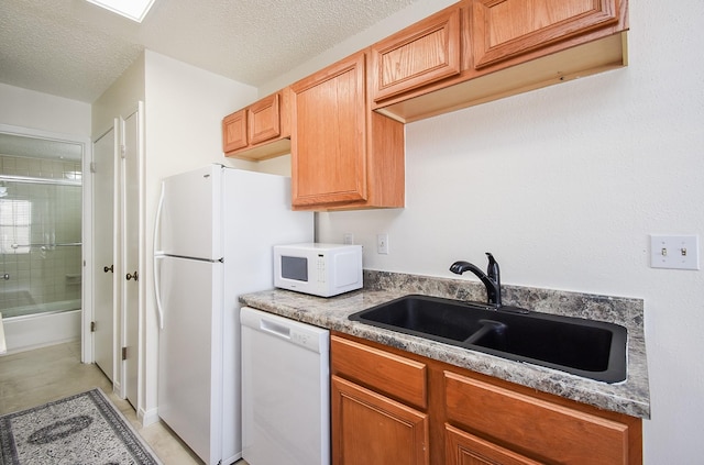 kitchen with light stone counters, sink, white appliances, and a textured ceiling