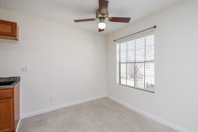 interior space with ceiling fan, sink, and a textured ceiling