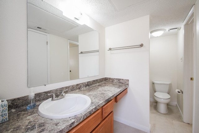 bathroom featuring vanity, toilet, and a textured ceiling