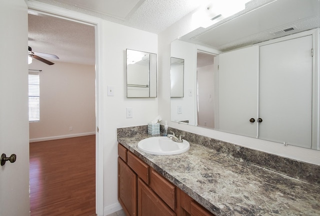 bathroom featuring hardwood / wood-style flooring, ceiling fan, vanity, and a textured ceiling