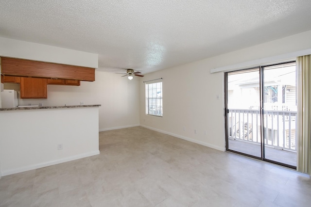 unfurnished living room featuring ceiling fan and a textured ceiling