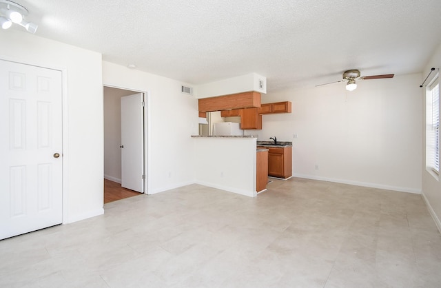 kitchen featuring white refrigerator, ceiling fan, sink, and a textured ceiling