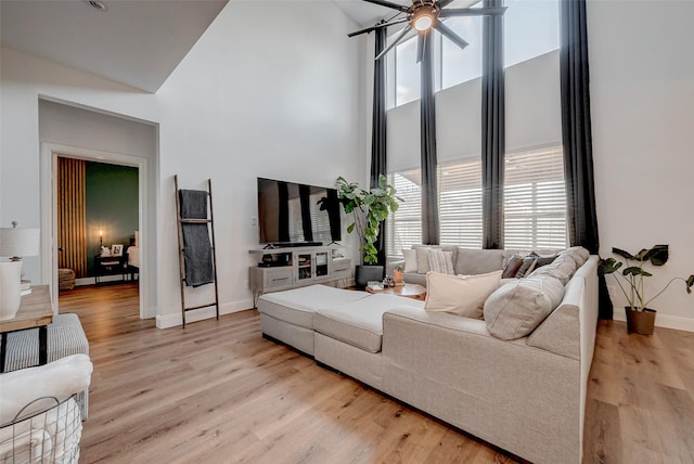 living room with ceiling fan, high vaulted ceiling, and light wood-type flooring