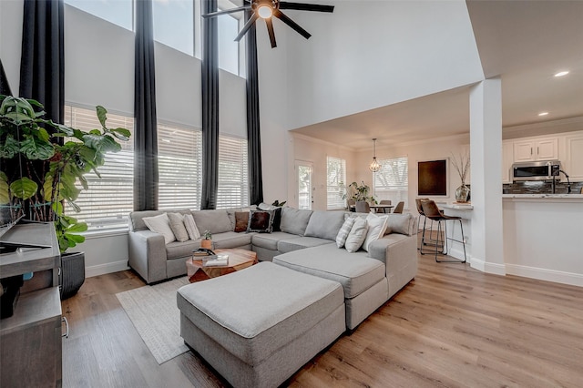 living room featuring plenty of natural light, ceiling fan, light hardwood / wood-style flooring, and ornamental molding