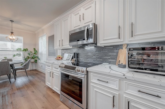 kitchen featuring crown molding, white cabinetry, stainless steel appliances, and pendant lighting