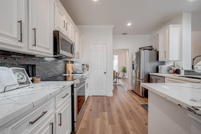 kitchen with sink, stainless steel appliances, white cabinets, light stone countertops, and decorative backsplash