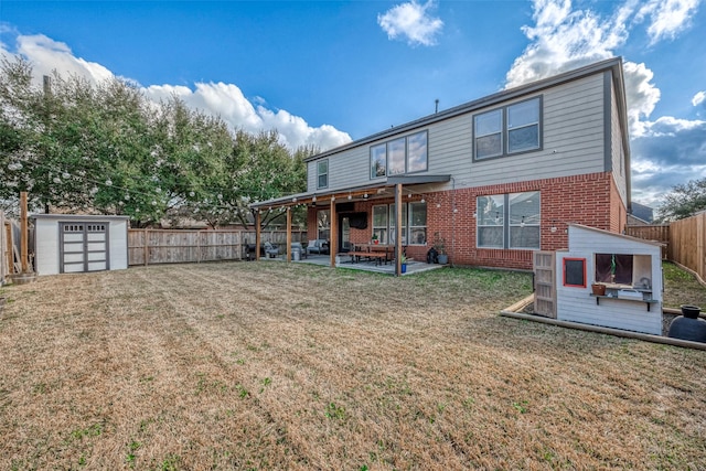 rear view of property with a storage unit, a lawn, and a patio area