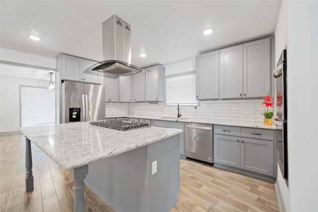 kitchen featuring light stone counters, stainless steel appliances, a kitchen island, and island range hood