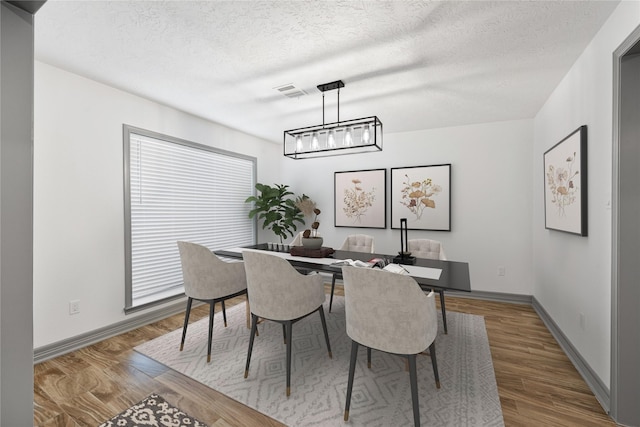 dining area featuring hardwood / wood-style flooring, a chandelier, and a textured ceiling