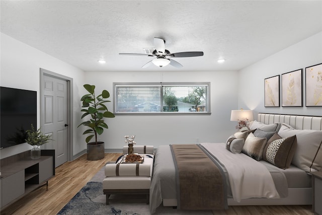 bedroom featuring ceiling fan, a textured ceiling, and light wood-type flooring