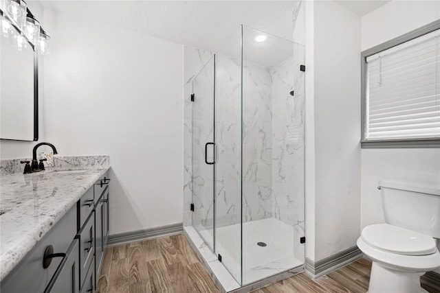 bathroom featuring vanity, wood-type flooring, a shower with door, and toilet