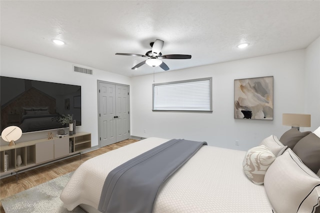 bedroom featuring a textured ceiling, wood-type flooring, a closet, and ceiling fan