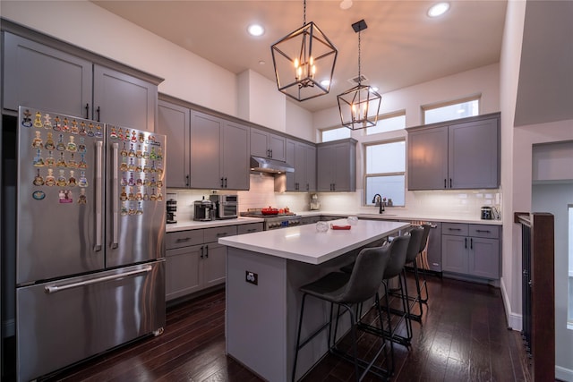 kitchen with a breakfast bar, stainless steel appliances, a center island, dark hardwood / wood-style flooring, and decorative light fixtures