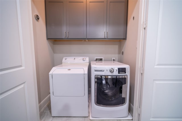 clothes washing area featuring cabinets and washing machine and dryer