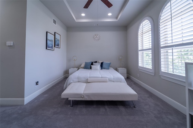 carpeted bedroom with ceiling fan and a tray ceiling