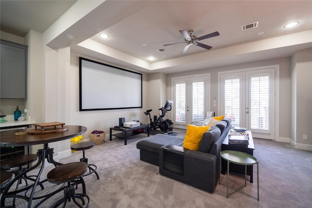 cinema featuring a raised ceiling, light carpet, ceiling fan, and french doors