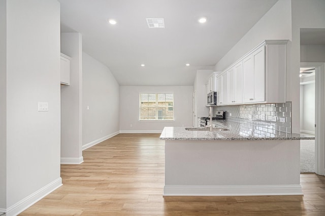 kitchen with light stone counters, stainless steel appliances, tasteful backsplash, and light wood finished floors