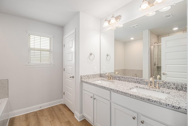 bathroom featuring visible vents, a shower stall, wood finished floors, and a sink