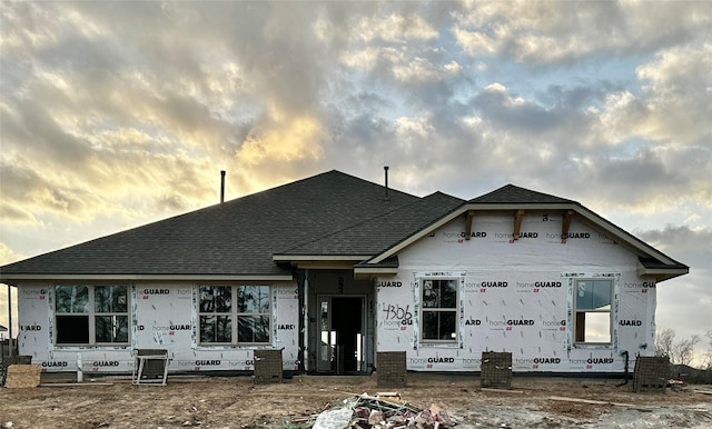 rear view of property featuring a shingled roof