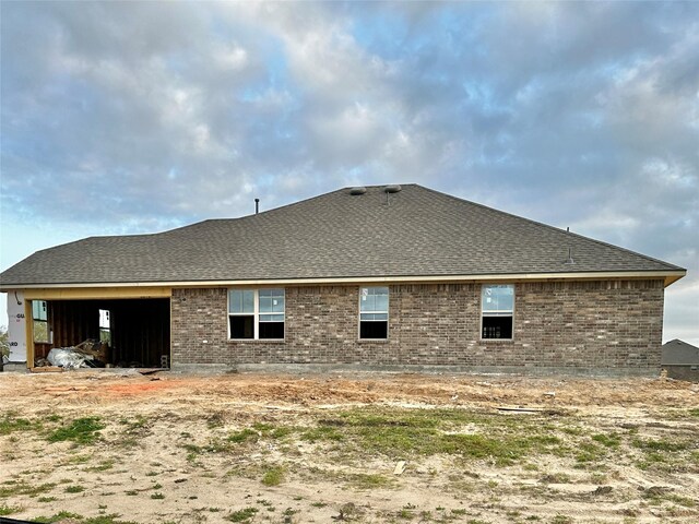 back of property with brick siding and a shingled roof