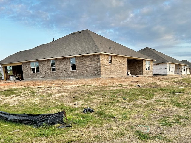 rear view of house with brick siding and a shingled roof