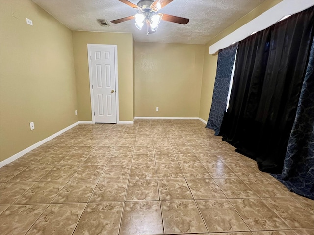 tiled spare room featuring a textured ceiling, a ceiling fan, visible vents, and baseboards