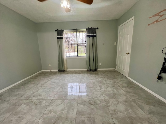 spare room with a textured ceiling, baseboards, and a ceiling fan