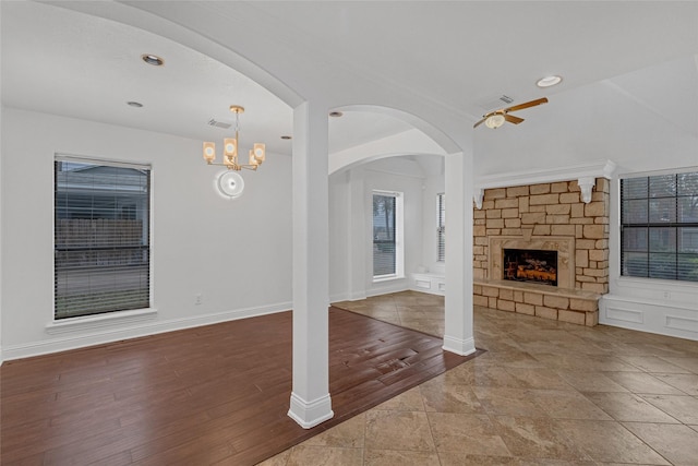 unfurnished living room featuring an inviting chandelier, hardwood / wood-style floors, and a stone fireplace