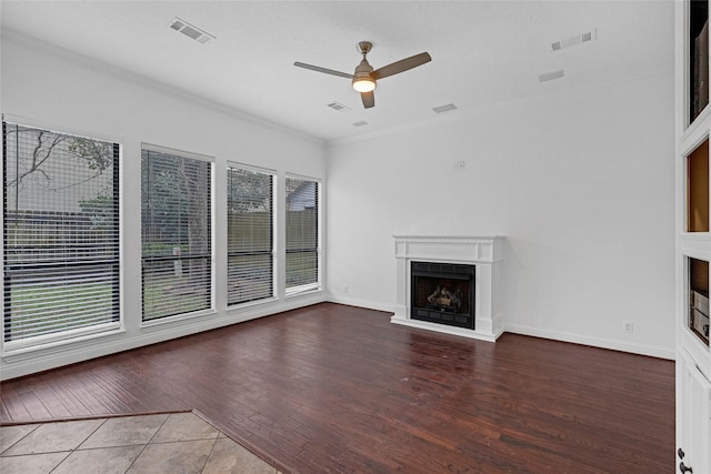 unfurnished living room featuring wood-type flooring, a healthy amount of sunlight, ceiling fan, and crown molding