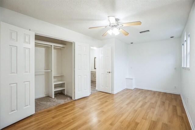 unfurnished bedroom with ceiling fan, a closet, light hardwood / wood-style flooring, and a textured ceiling