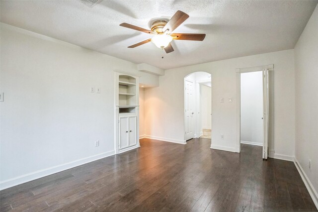 unfurnished room with dark hardwood / wood-style flooring, ceiling fan, built in shelves, and a textured ceiling