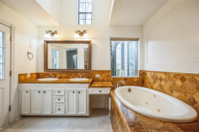 bathroom with vanity, tiled bath, tile patterned floors, and a textured ceiling