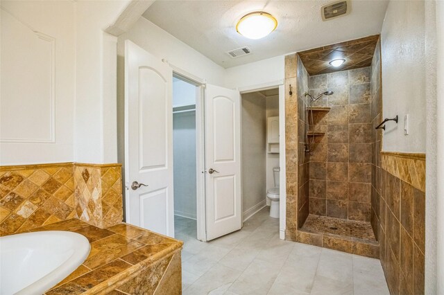 bathroom with shower with separate bathtub, tile walls, and toilet